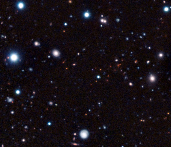 Скопление галактик CL J1449+0856 на снимке видно, как множество тусклых красноватых объектов в центральной части снимка. 