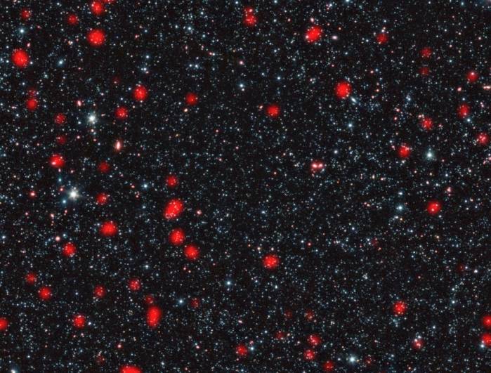 Удаленные ультраяркие инфракрасные галактики на снимке отмечены красным. Фоновый инфракрасный снимок был сделан космическим телескопом «Спитцер». Фото ESO, APEX (MPIfR/ESO/OSO), A. Weiss et al., NASA Spitzer Science Center