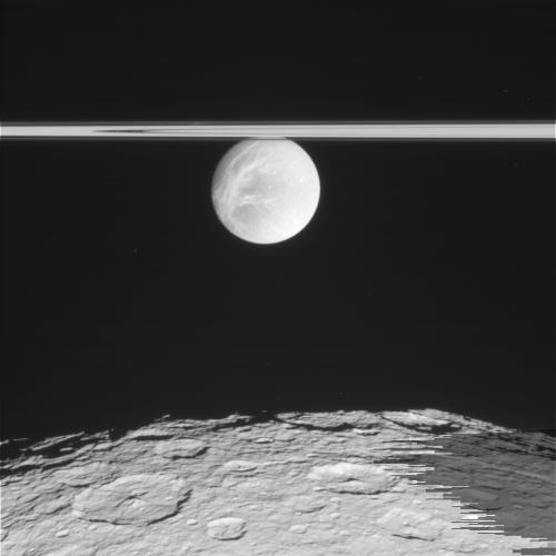 Поверхность Реи. Выше - ещё однин спутник Сатурна, Диона, на фоне колец своей планеты. Фото NASA / JPL / Space Science Institute.